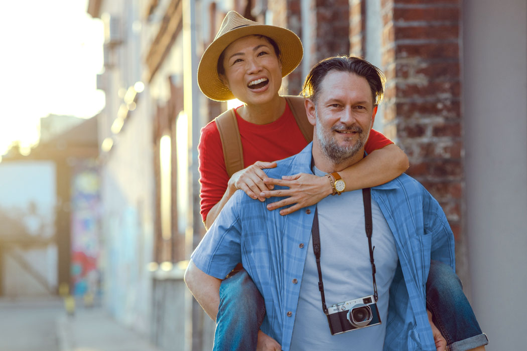 Man carrying a woman on his back smiling.